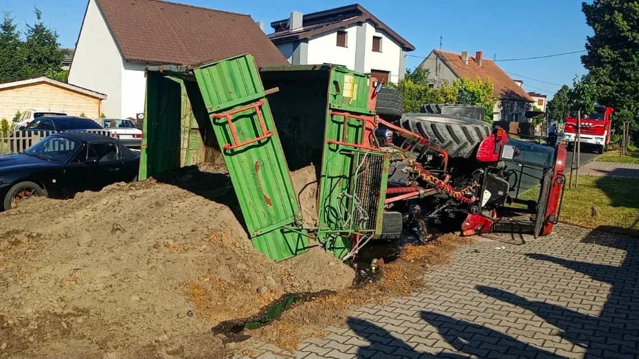 Przewrócone ciągnik i przyczepa, ziemia na drodze, kierowca bez uprawnień